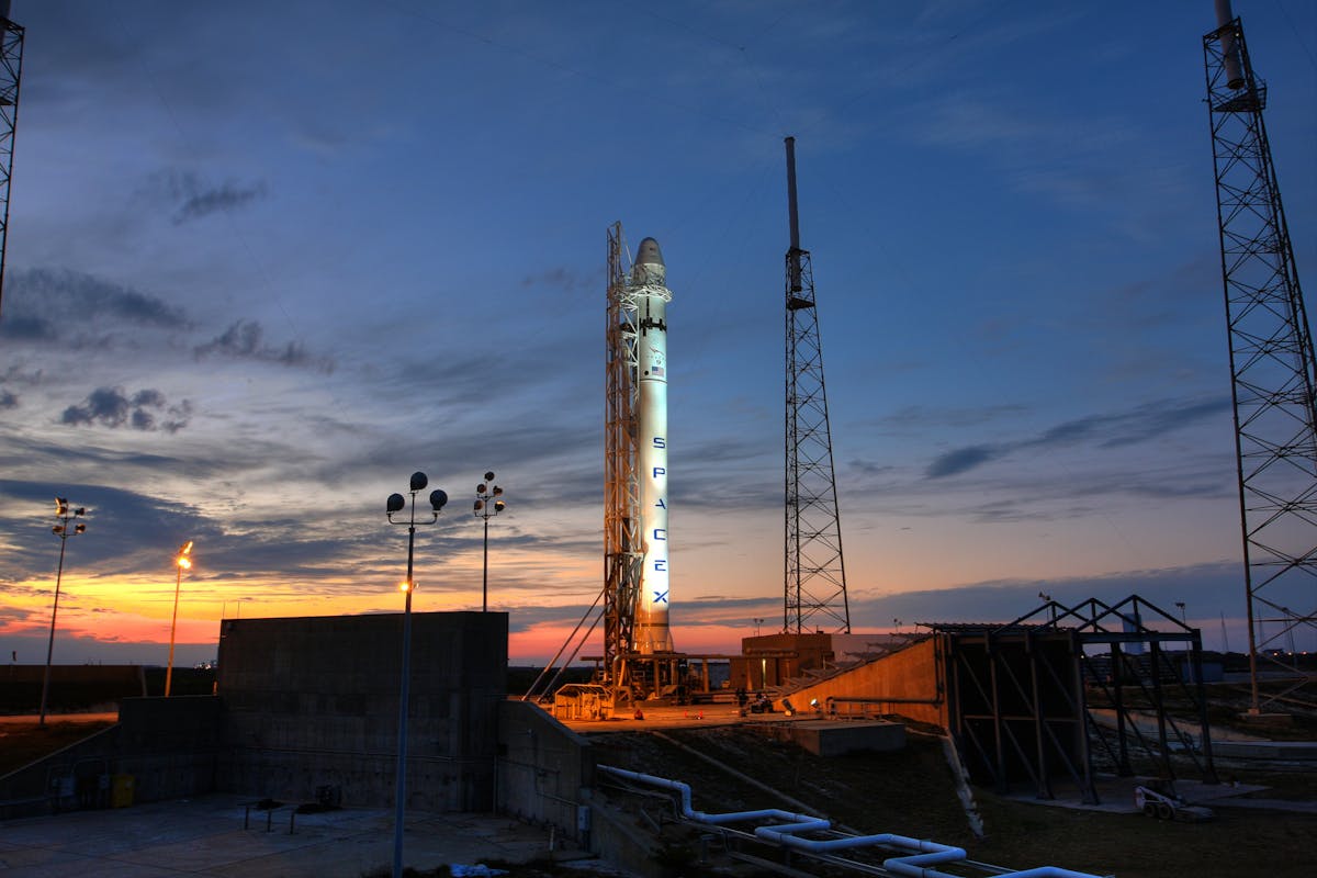 Solid rocket installed on metal launch construction in spaceport and ready for taking off against colorful sunset sky