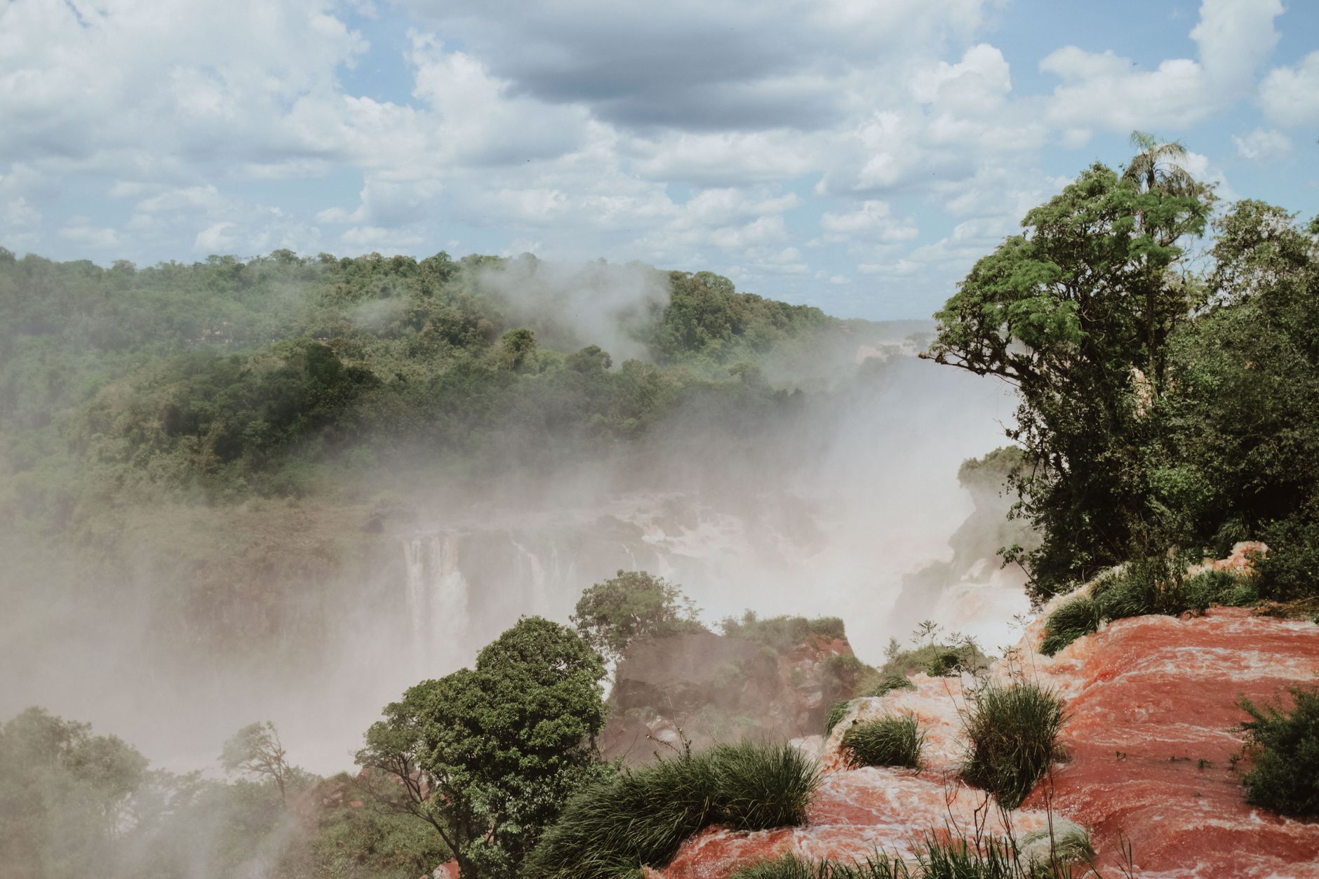 Scenic view of Iguazu Falls with mist and lush greenery. Perfect for nature and travel enthusiasts.