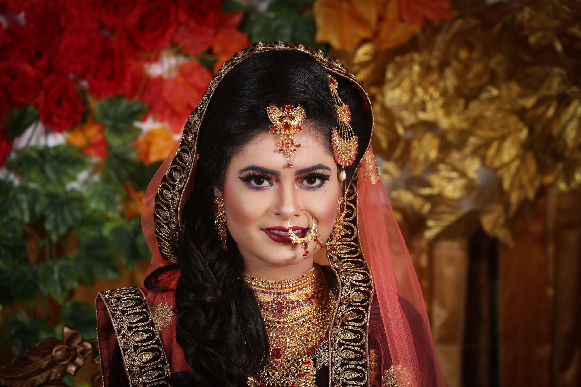 Elegant Bengali bride in traditional attire with vibrant jewelry and veil.