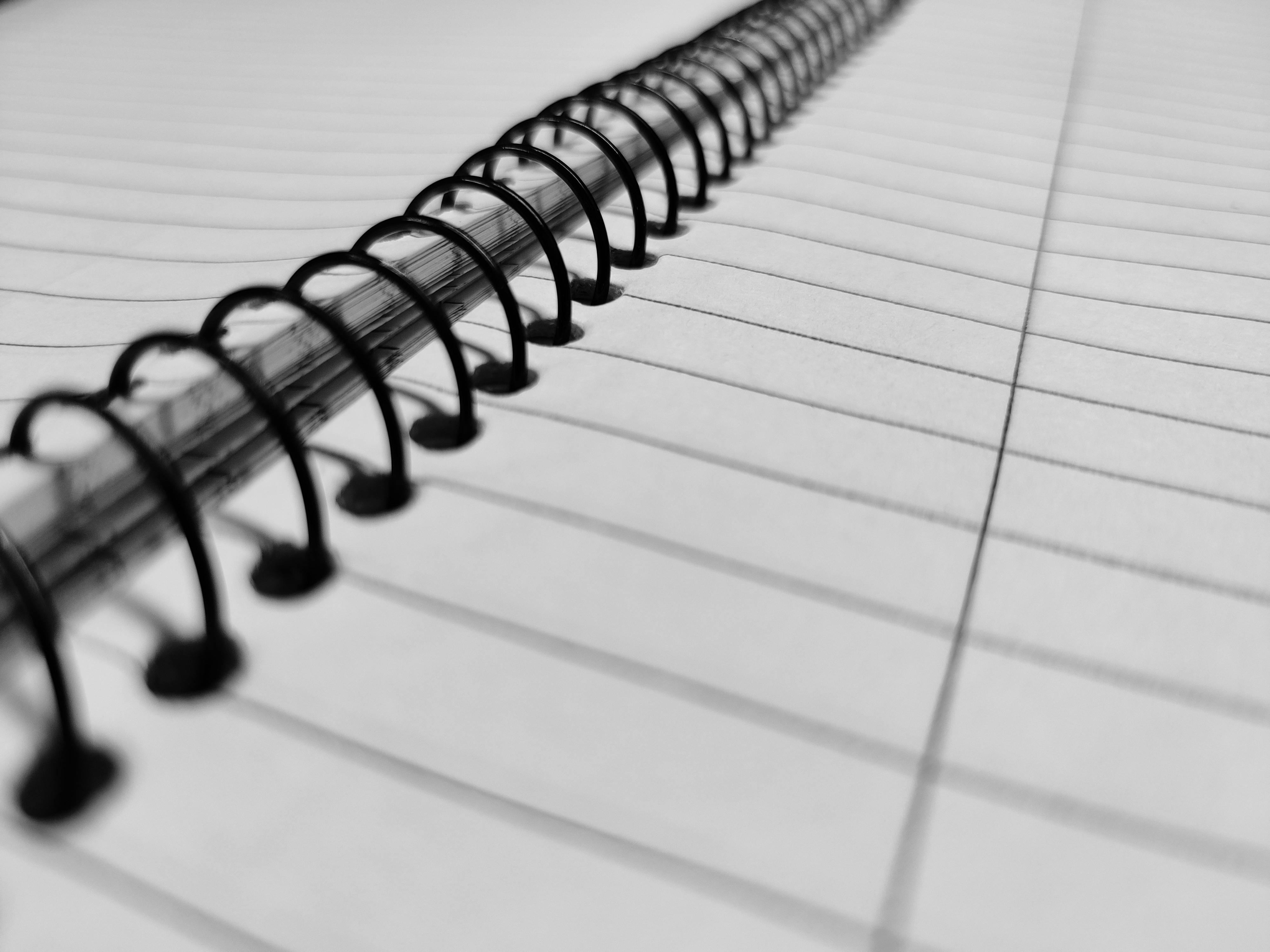 spiral notebook with black lines in close up photography
