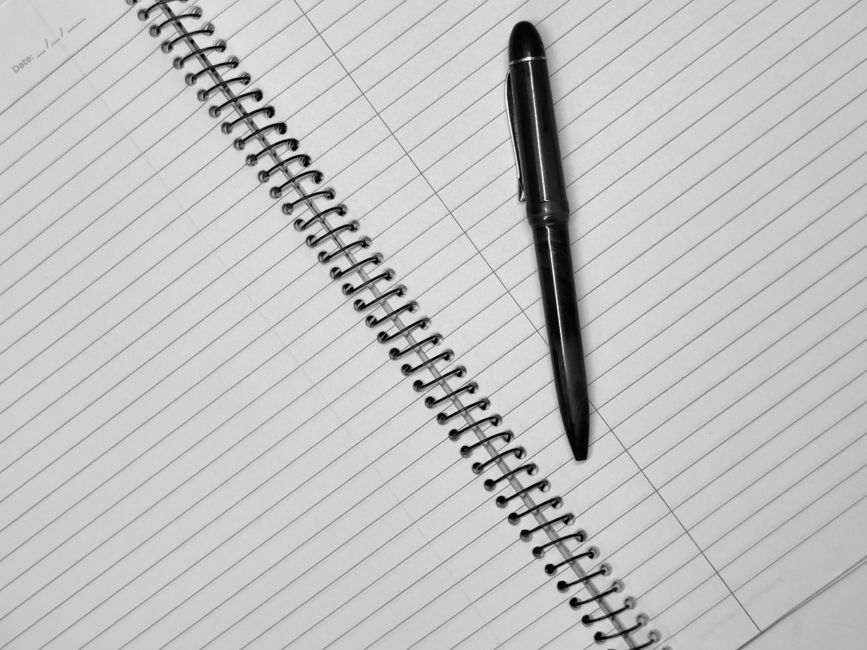 How Do I Write My Essay? A Step-by-Step Guide for 2026 2 Close-up of a black pen resting on an open spiral notebook with lined pages.