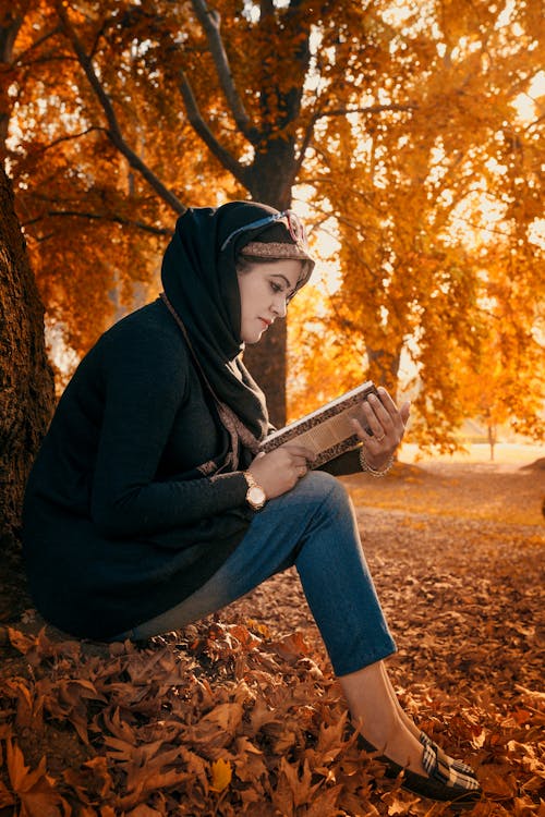 Woman Reading a Book Near a Tree