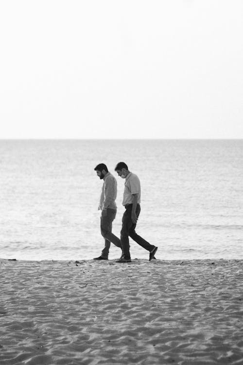 Black and White Photo of Men Walking on a Beach