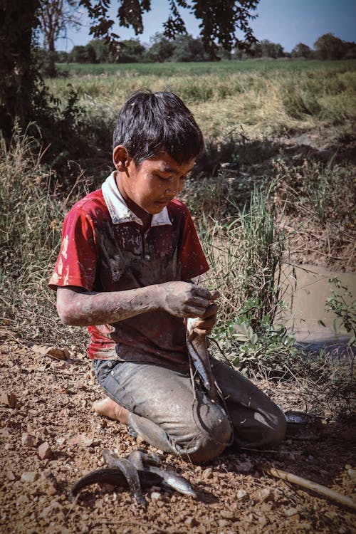 Boy Sitting in Mud Outdoors 