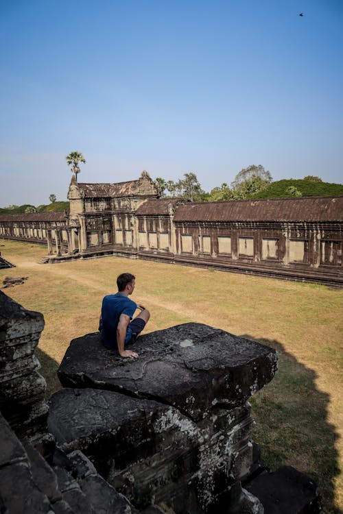 Man Sitting on Rock next to Neglected Palace