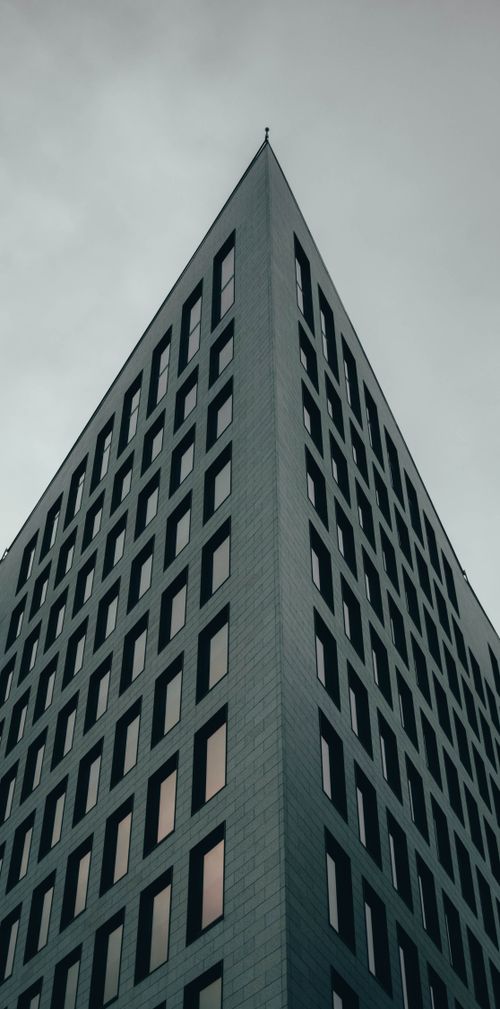 Free Striking low angle view of a modern skyscraper featuring symmetrical architecture and a grayscale facade. Stock Photo