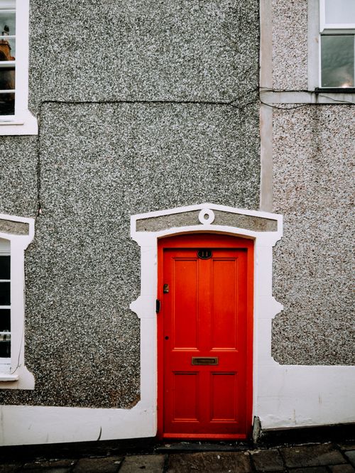 Free Eye-catching red door set against a textured gray wall, perfect for architectural themes. Stock Photo