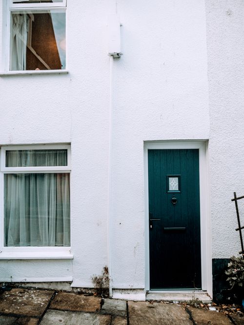 Free A white building facade with a distinct blue door and window, highlighting urban architecture. Stock Photo