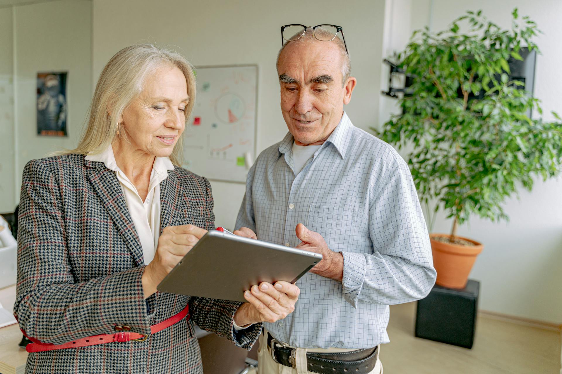 Senior professionals collaborating on a project using a digital tablet in a modern office setting.