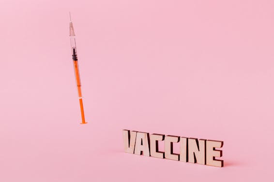 A Syringe and Vaccine Text on Pink Background