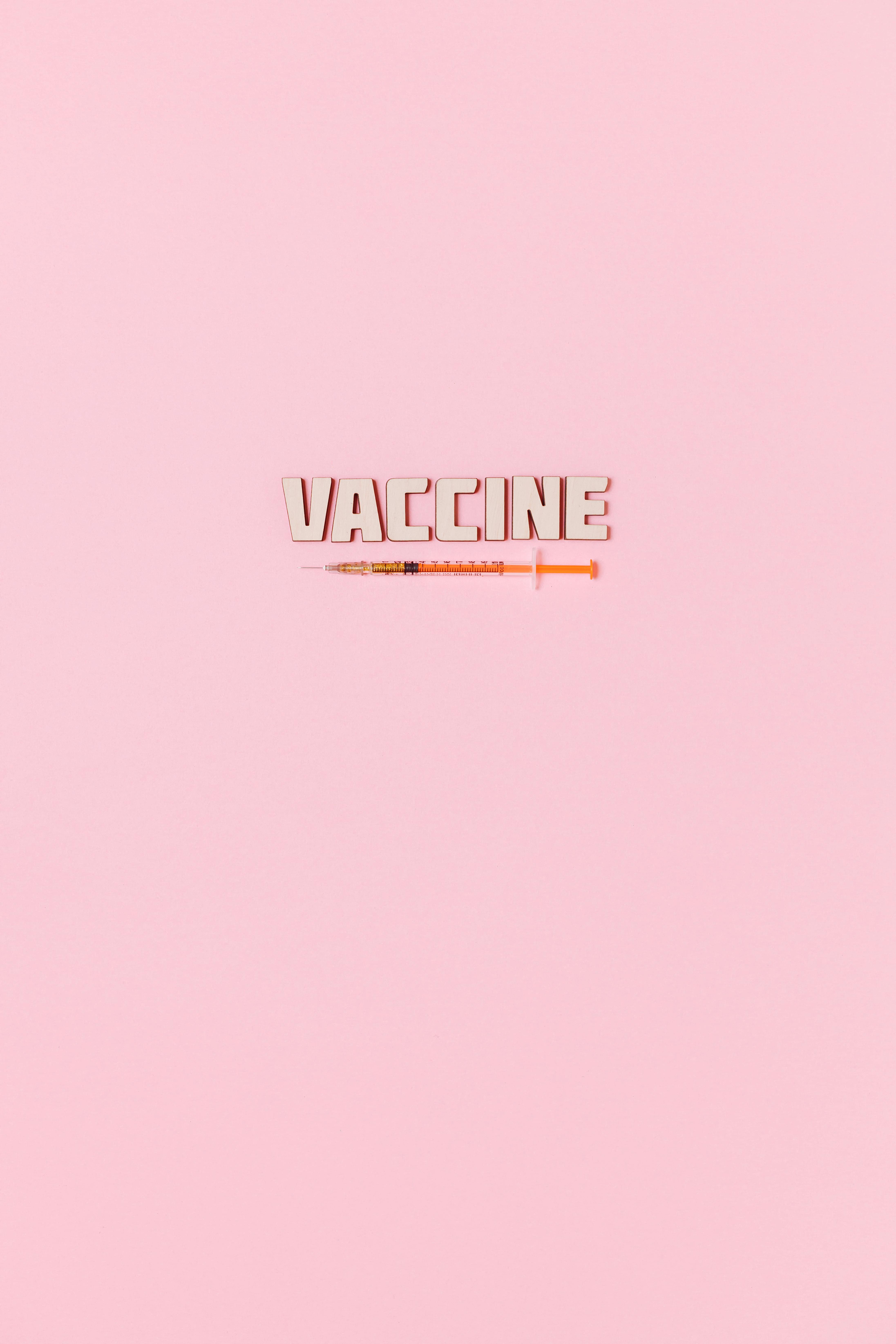 a syringe and vaccine text on pink background