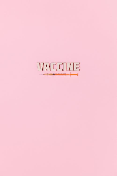 A Syringe and Vaccine Text on Pink Background