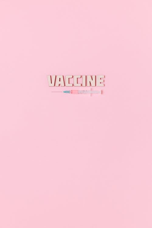 A Syringe and Vaccine Text on Pink Background