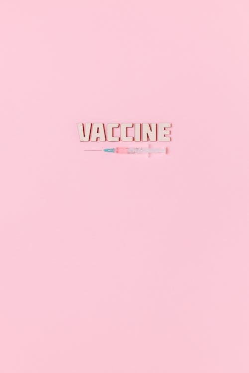 Free A Syringe and Vaccine Text on Pink Background Stock Photo