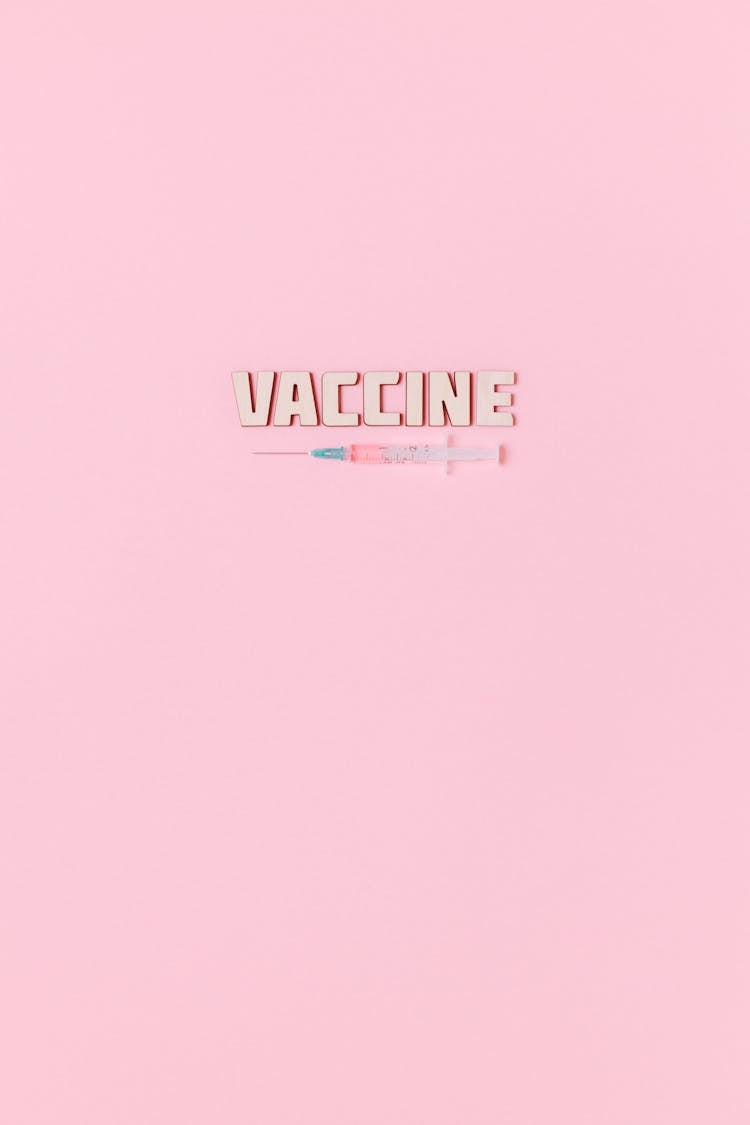 A Syringe And Vaccine Text On Pink Background