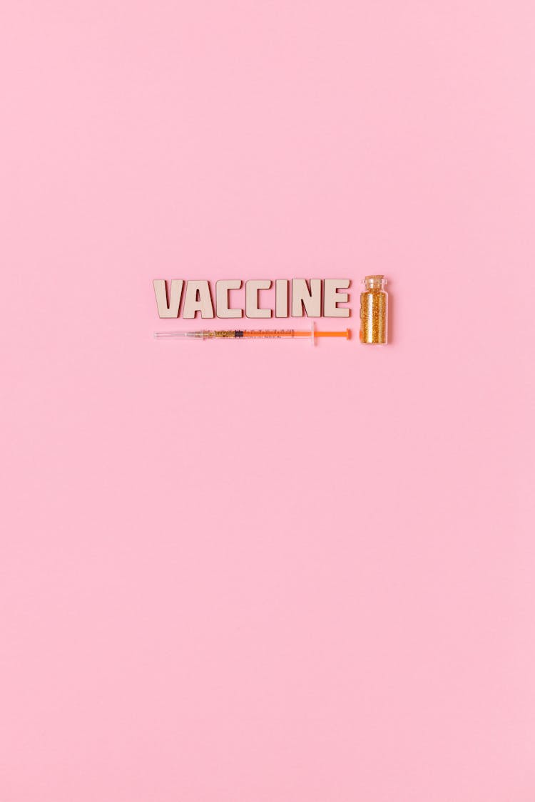 A Syringe And Vaccine Text On Pink Background