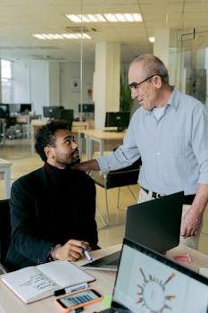 Two colleagues discussing work in a bright, modern office setting.