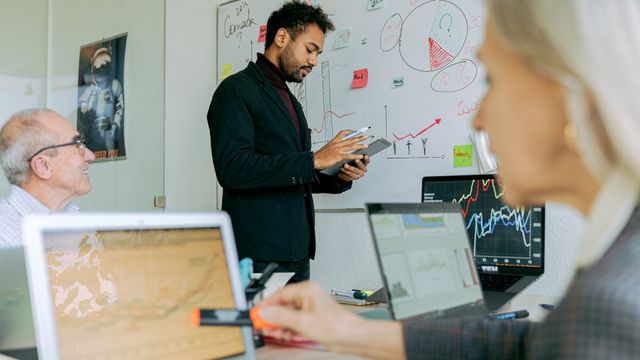 Technology leader presenting a plan to his team at a whiteboard