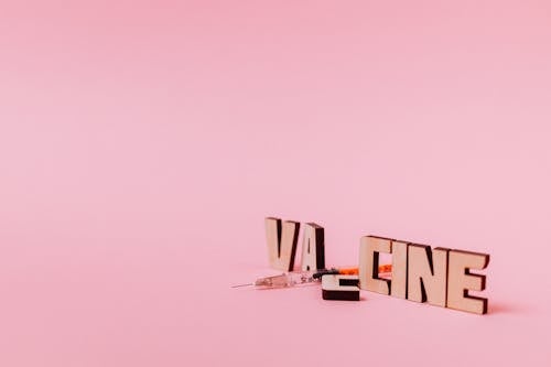 A Syringe and Vaccine Text on Pink Background