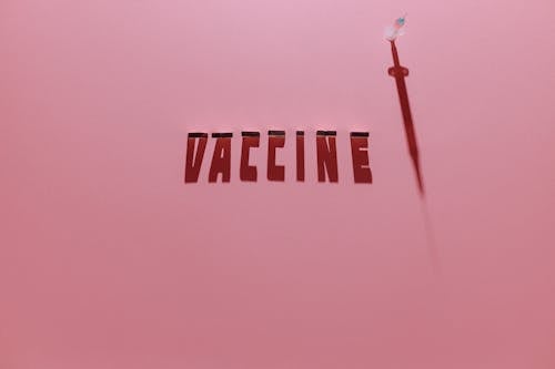 A Syringe and Vaccine Lettering Text on Pink Background