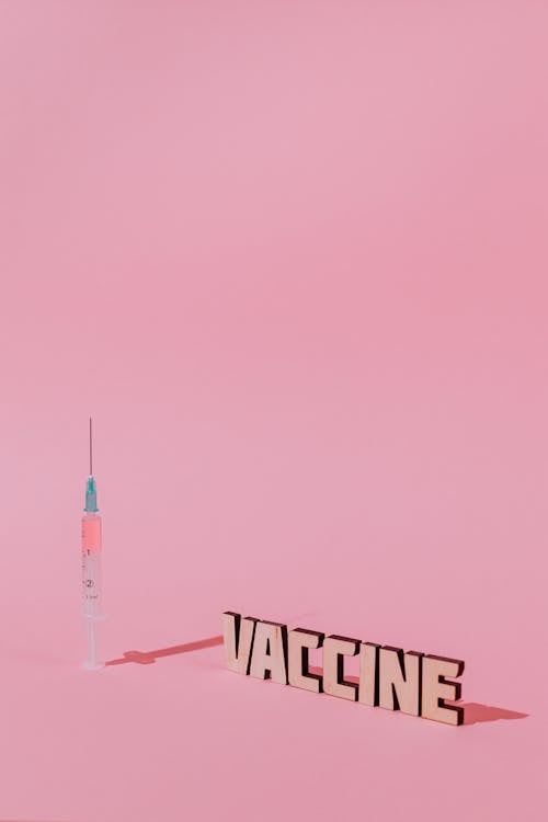 A Syringe and Vaccine Lettering Text on Pink Background