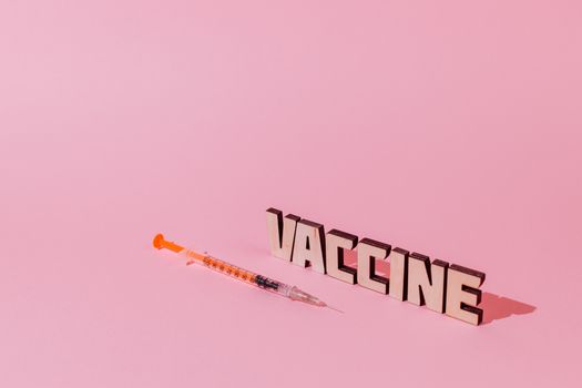 粉色背景上的注射器和“疫苗”文本，象征着医疗保健和免疫的概念