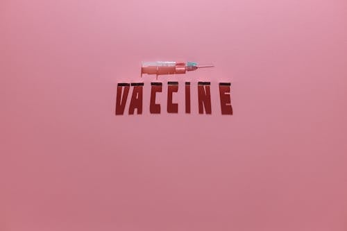 A Syringe and Vaccine Lettering Text on Pink Background