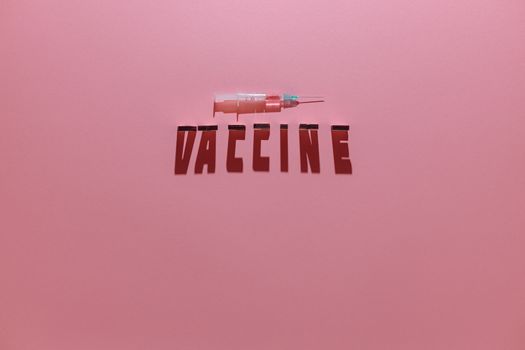一张粉红色背景上印有“疫苗”字样的注射器接种疫苗概念图