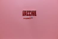 A Syringe and Vaccine Lettering Text on Pink Background