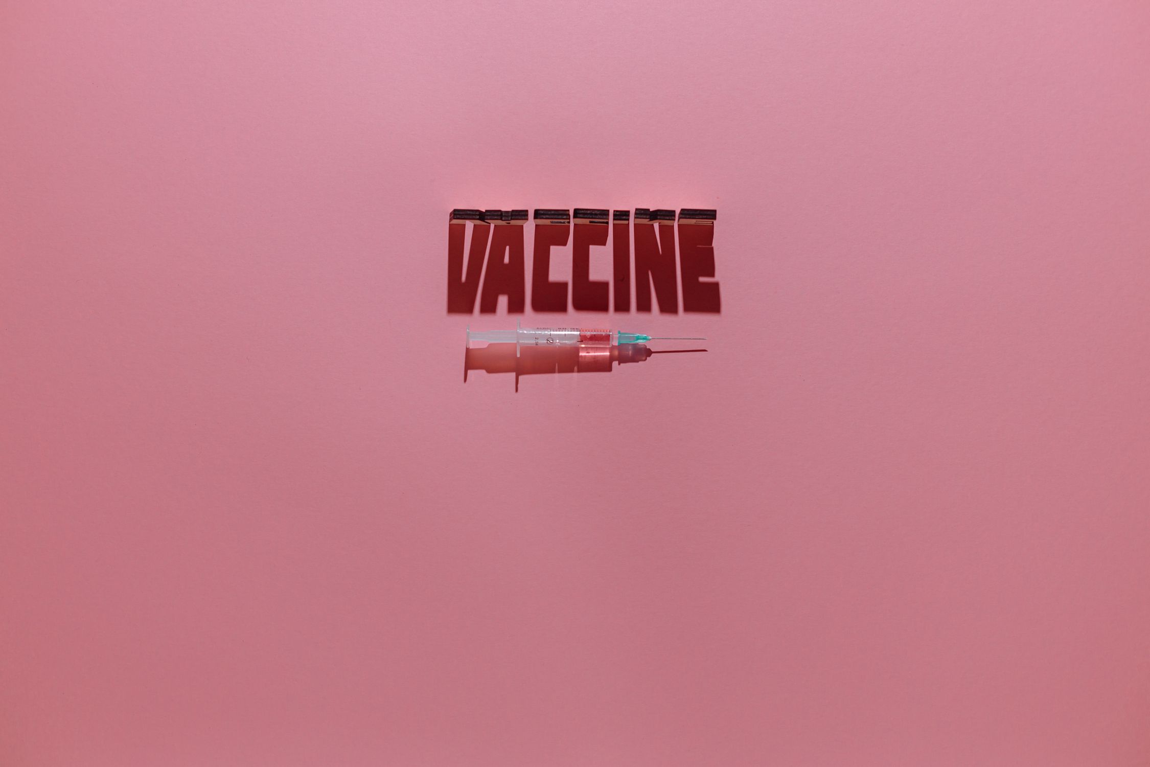 Syringe Lettering A Syringe and Vaccine Lettering Text on Pink Background · Free Stock Photo