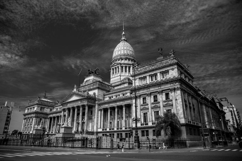 Imagen monocromática de un majestuoso edificio del capitolio con cúpula y estatuas.