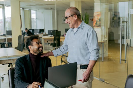 Two diverse professionals engage in a friendly conversation in a modern office setting.