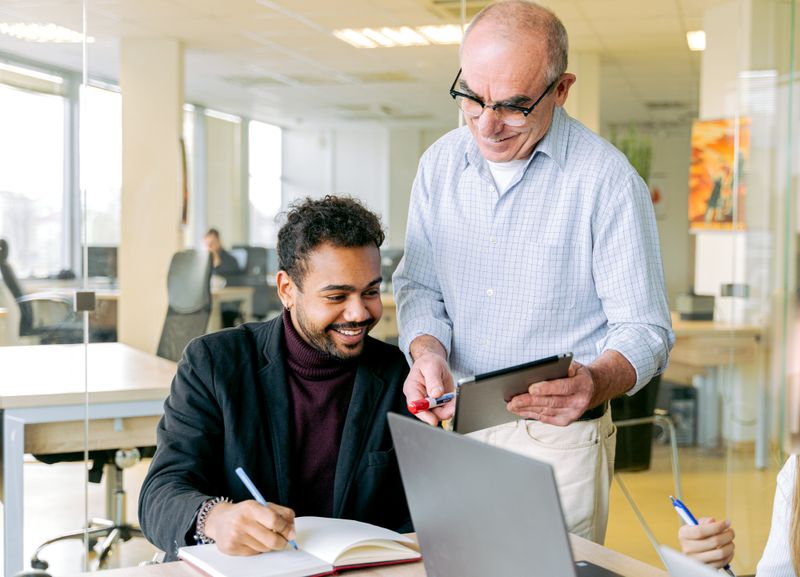Two colleagues in a one to one coaching discussion at a desk