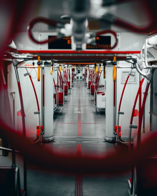 Free Symmetrical view inside an empty subway train with red accents and handles. Stock Photo