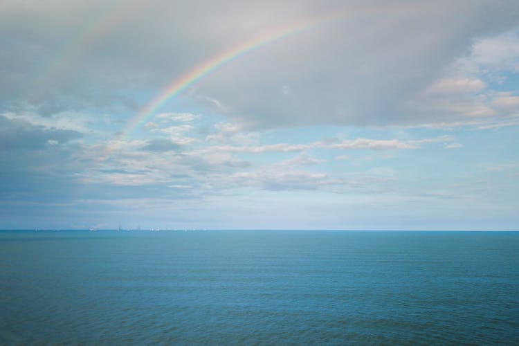 Spectacular Endless Sea Against Cloudy Blue Sky With Rainbow