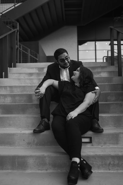 Happy young couple holding hand while relaxing on staircase in building