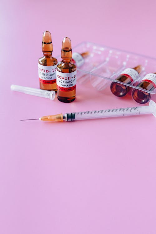 Free Covid_19 Vaccine In Vials And Syringe On Purple Background Stock Photo