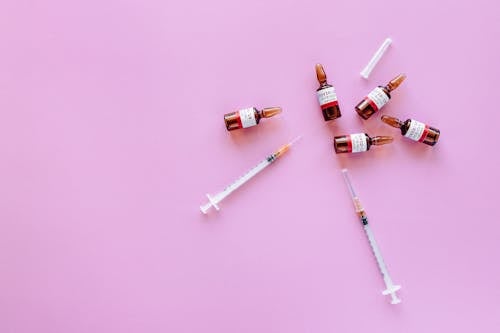 Corona Virus Vaccine And Syringes On Purple Background