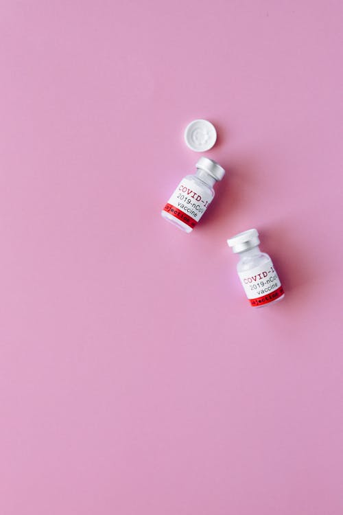Two Covid Vials on Pink Surface