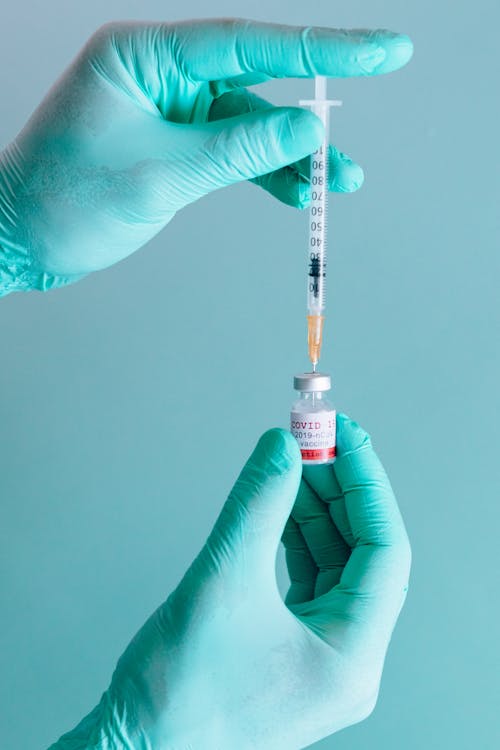 Free A Person Holding a Syringe and a Vial Stock Photo