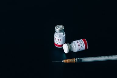 Vaccine vials and a syringe laid out on the bench