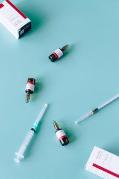 蓝色表面上平放着医用小瓶和注射器，体现了疫苗接种的概念