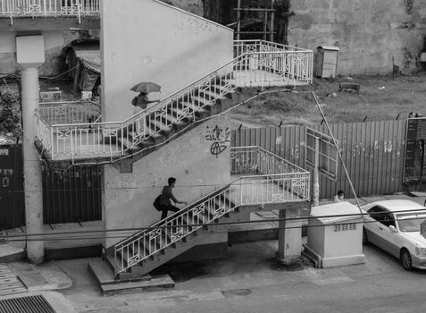 Monochrome street scene depicting a person ascending a staircase in Yangon, Myanmar.