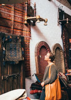 一位女士在充满活力的室内市场里欣赏着传统地毯和纺织品