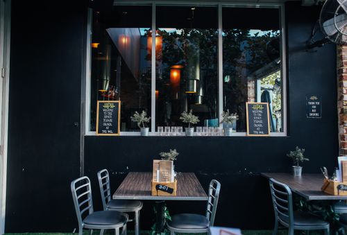 Free Stylish outdoor cafe with wooden tables and chairs, perfect for casual dining. Stock Photo