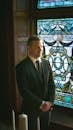 Happy groom in classic suit in church with candles