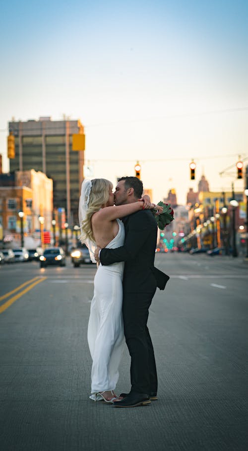 Bride and groom kissing and bonding on asphalt road
