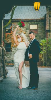 Full body of romantic newlywed couple in white wedding gown with blooming roses and formal suit with tie on street
