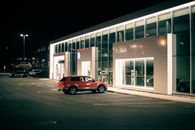 Modern SUV car parked near entrance of store selling new modern vehicles at night