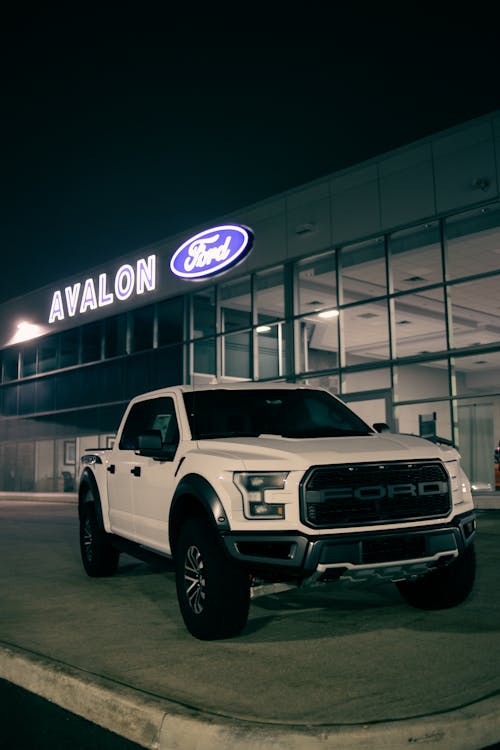 Pickup car parked near building with glowing signboard